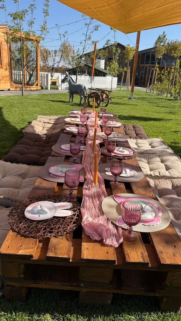 Wooden pallet table with pink party settings on grass with horse statue background