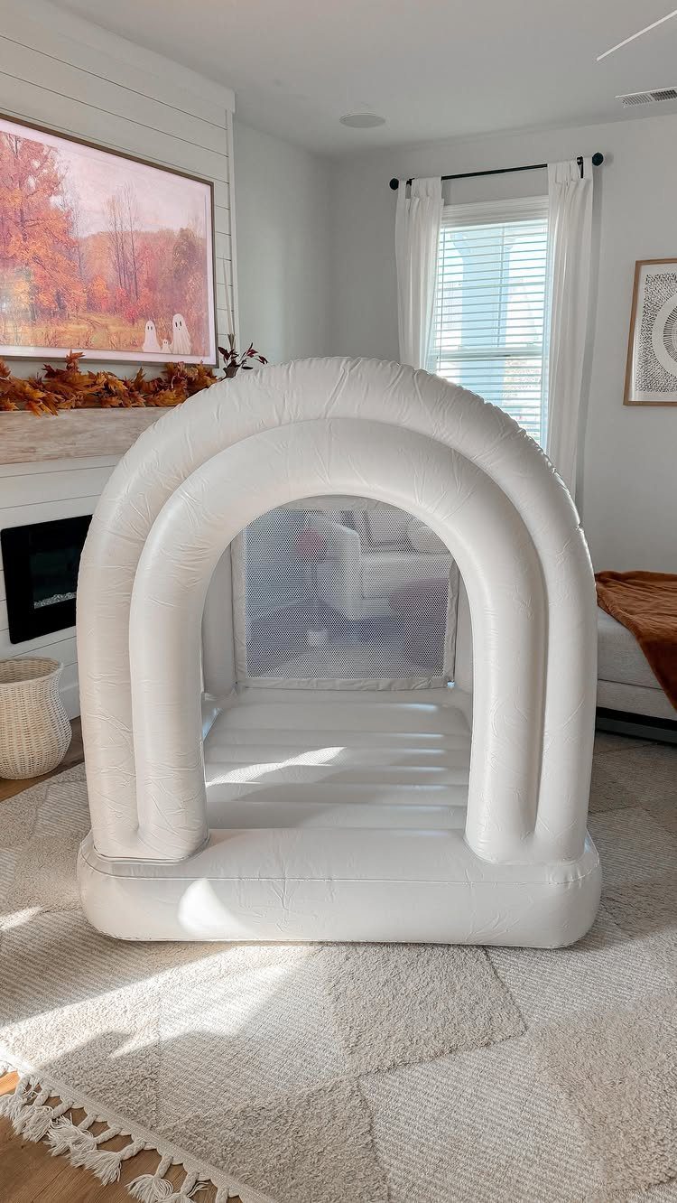 White inflatable arch bounce house set up on a rug in a living room.
