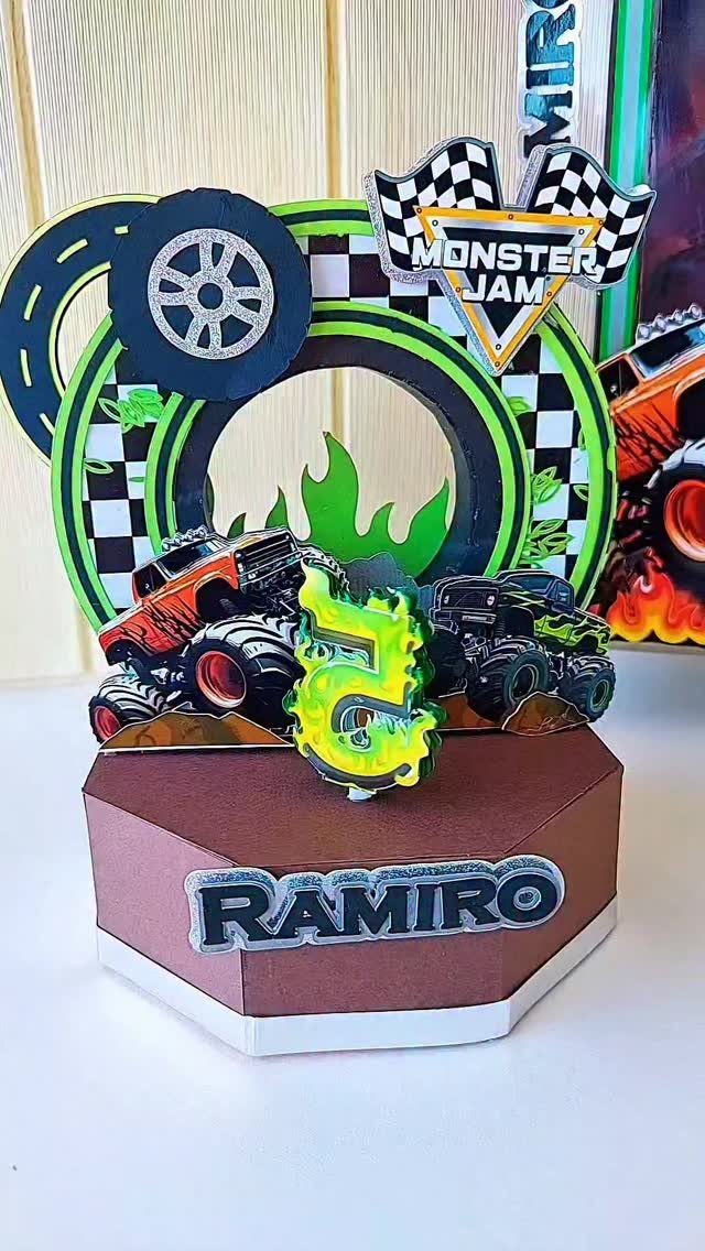 Monster truck birthday cake topper with trucks, tires, and the name Ramiro.