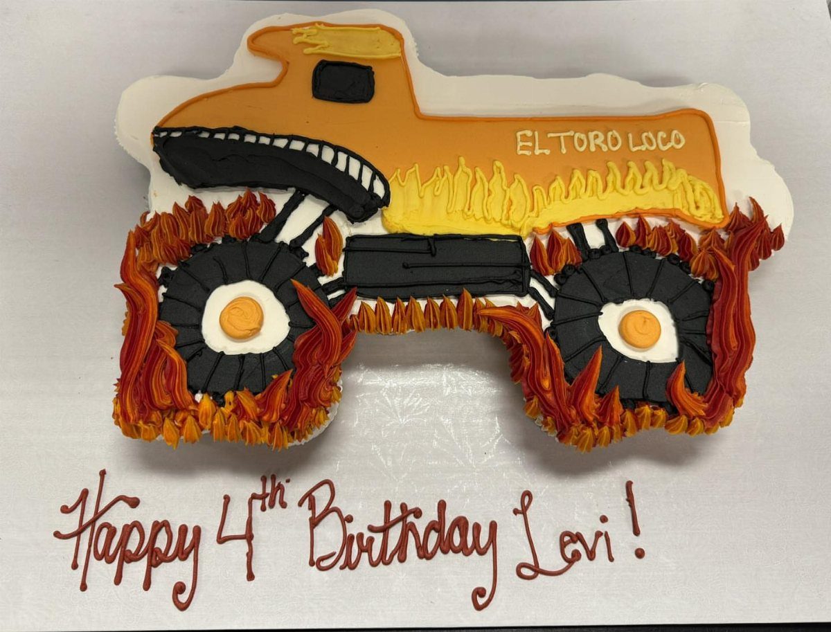 Monster truck cake with orange frosting and flames for a fourth birthday party.