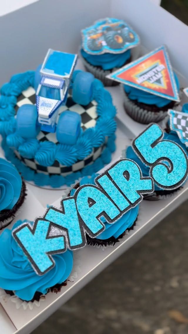 Blue monster truck cake and matching cupcakes with a glittery name sign.