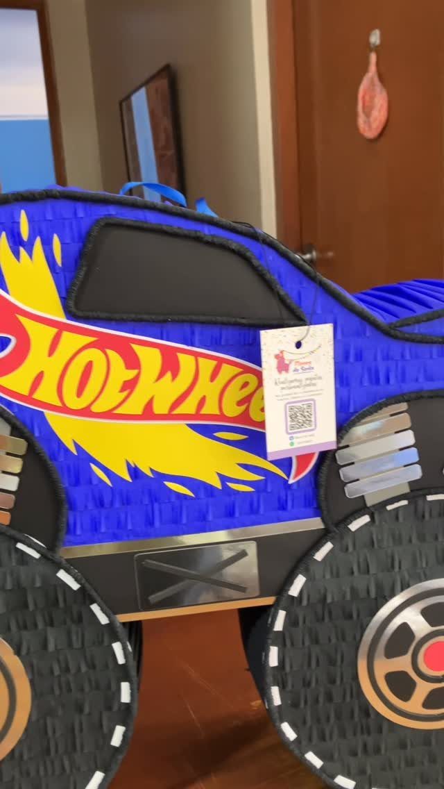 Blue Hot Wheels monster truck piñata with large black tires and flame graphics.