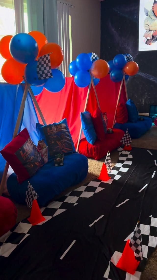 Race track party setup with teepees, balloons, and checkered flags on the floor.