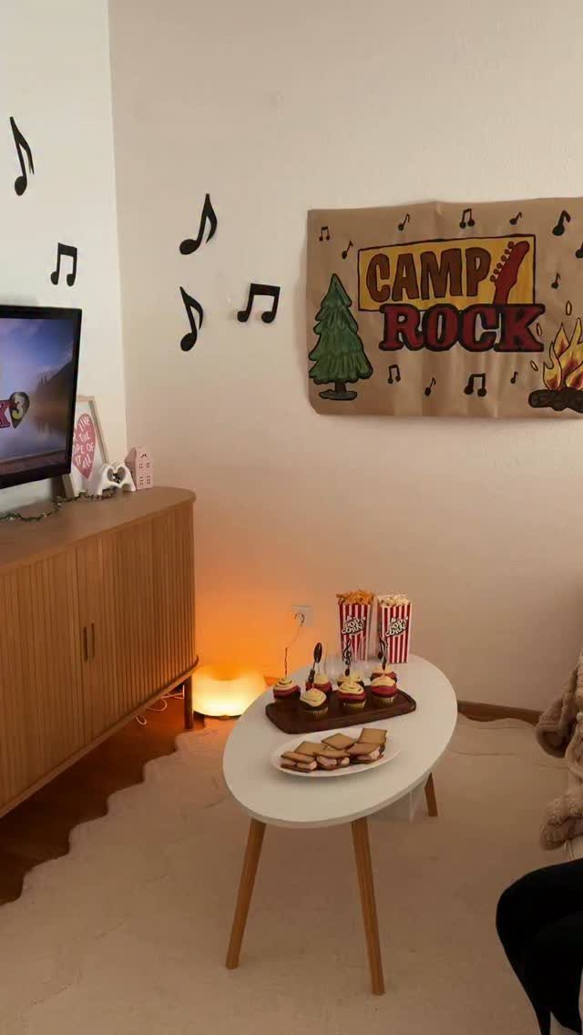 Living room movie setup with Camp Rock banner, snacks, and musical note decorations.