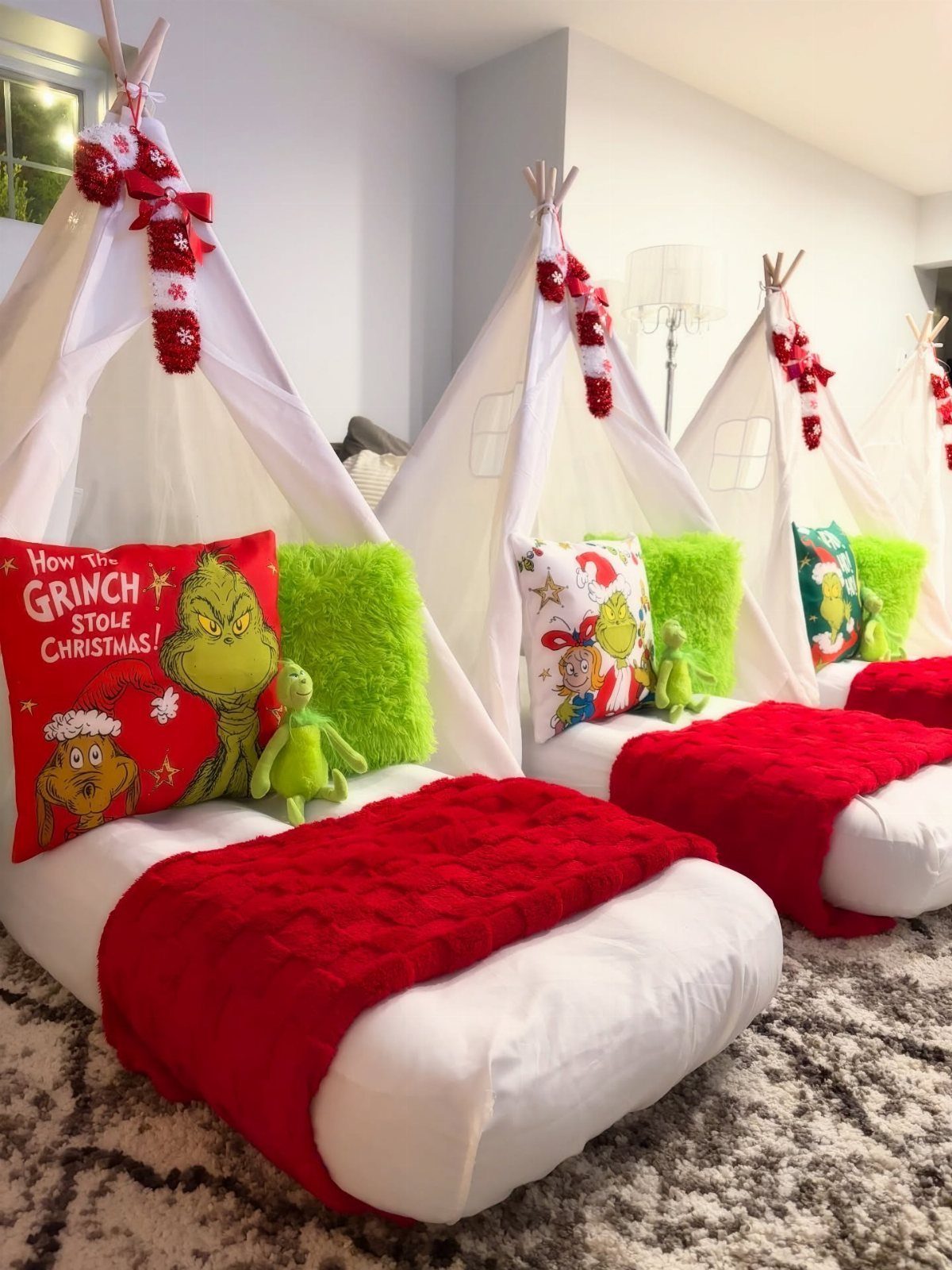 White teepee tents with red blankets and Grinch themed pillows for a sleepover.