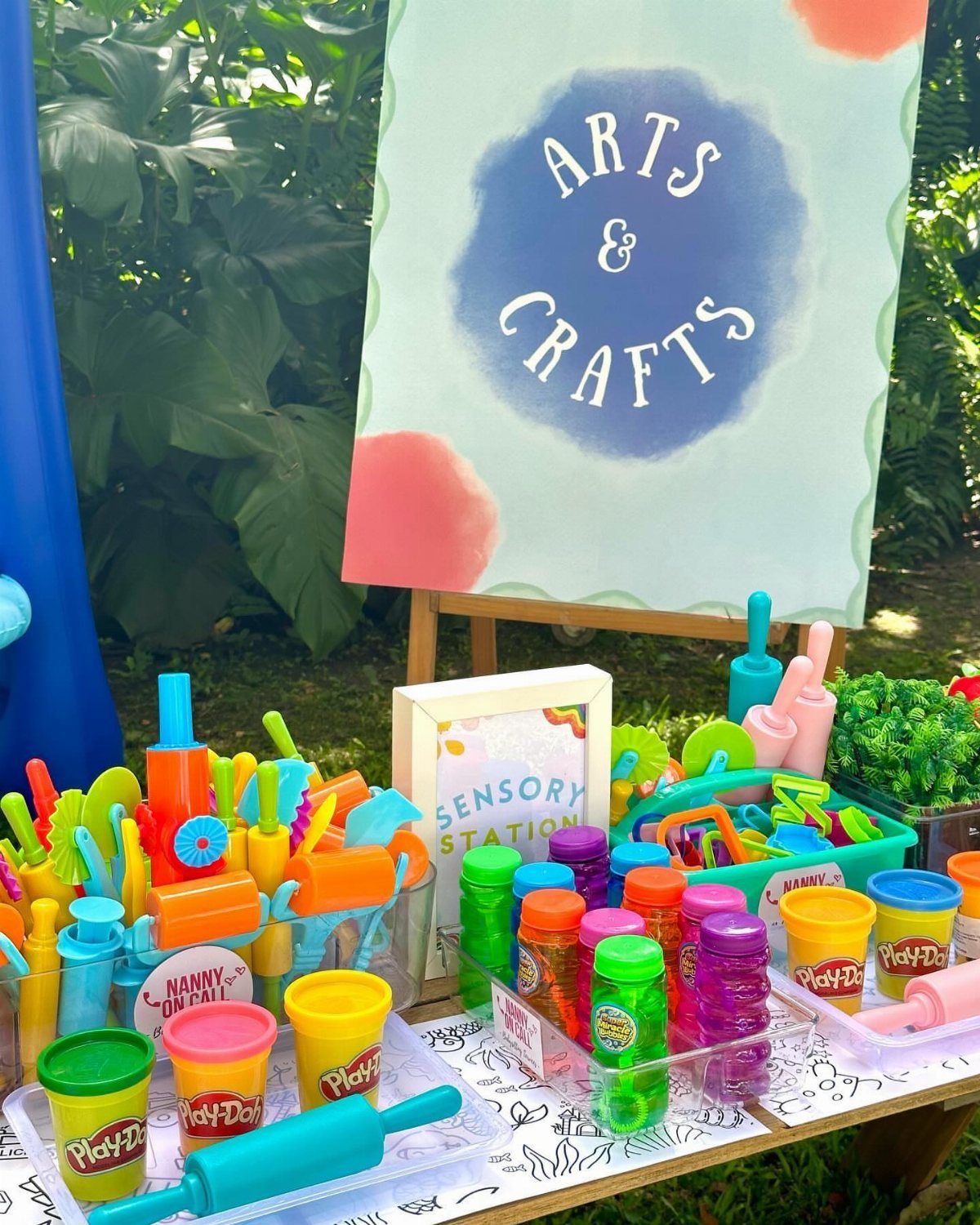 Arts and crafts station with colorful Play-Doh and tools on an outdoor table.