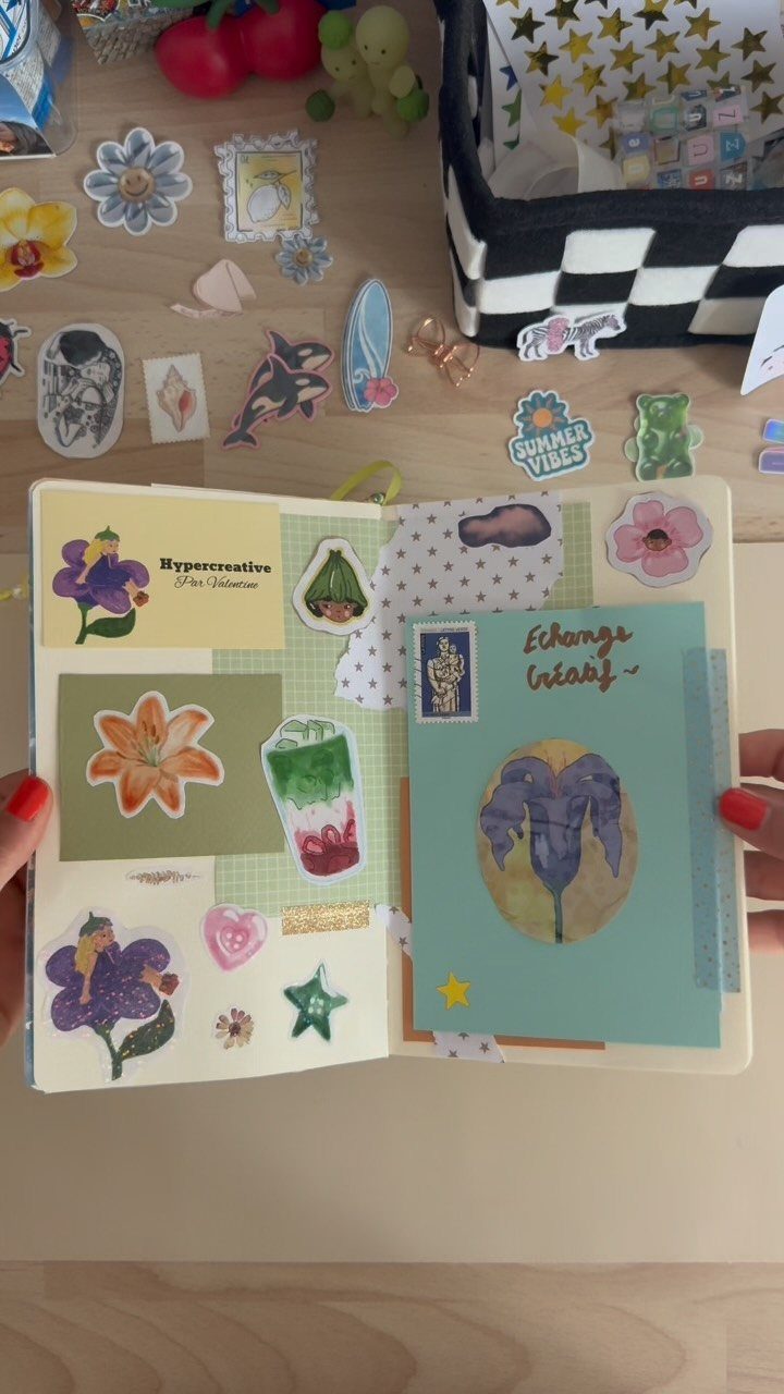 Open scrapbook with colorful floral stickers and drawings on a wooden table