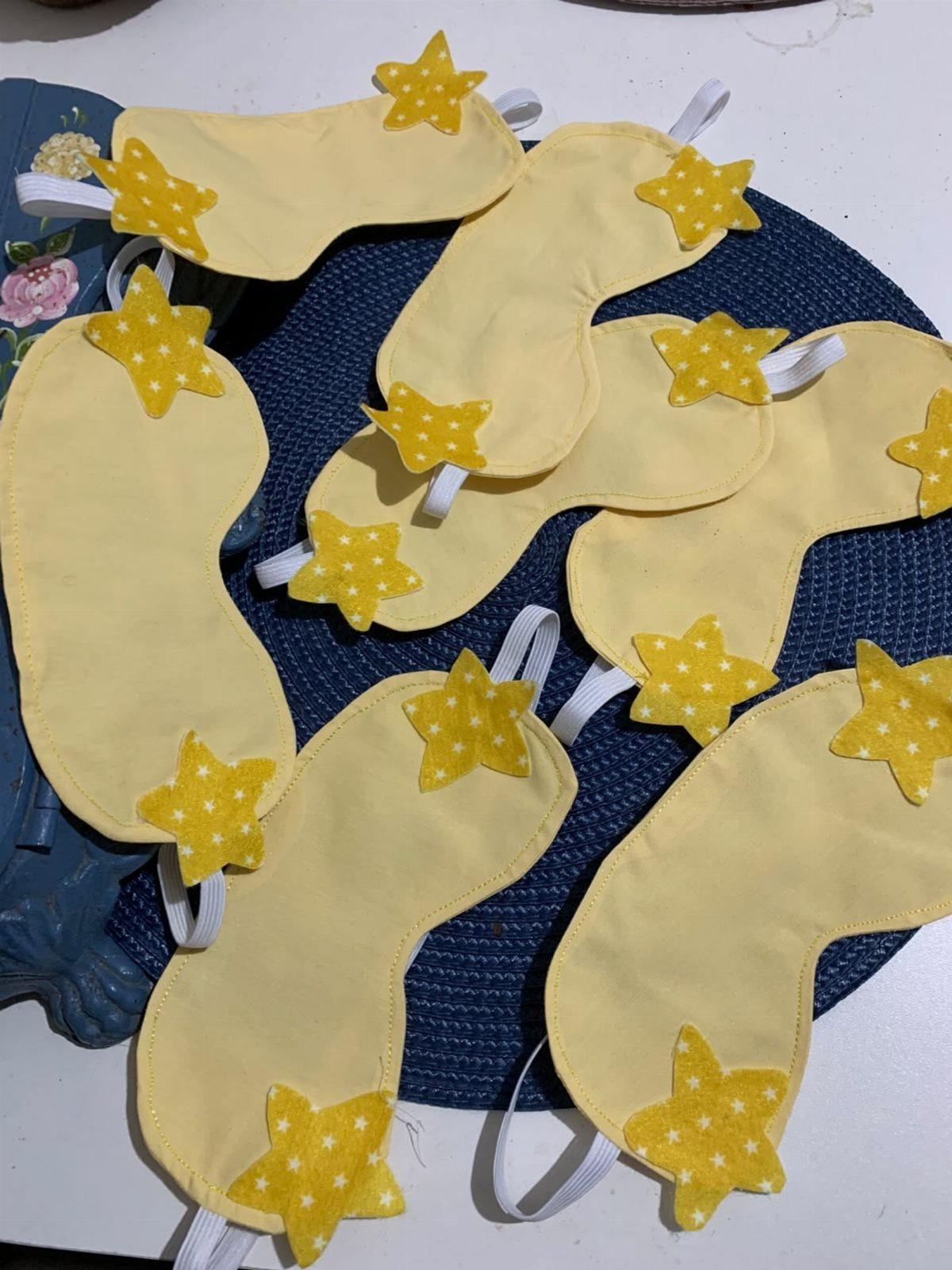 Yellow fabric sleep masks with star decorations resting on a blue woven mat.