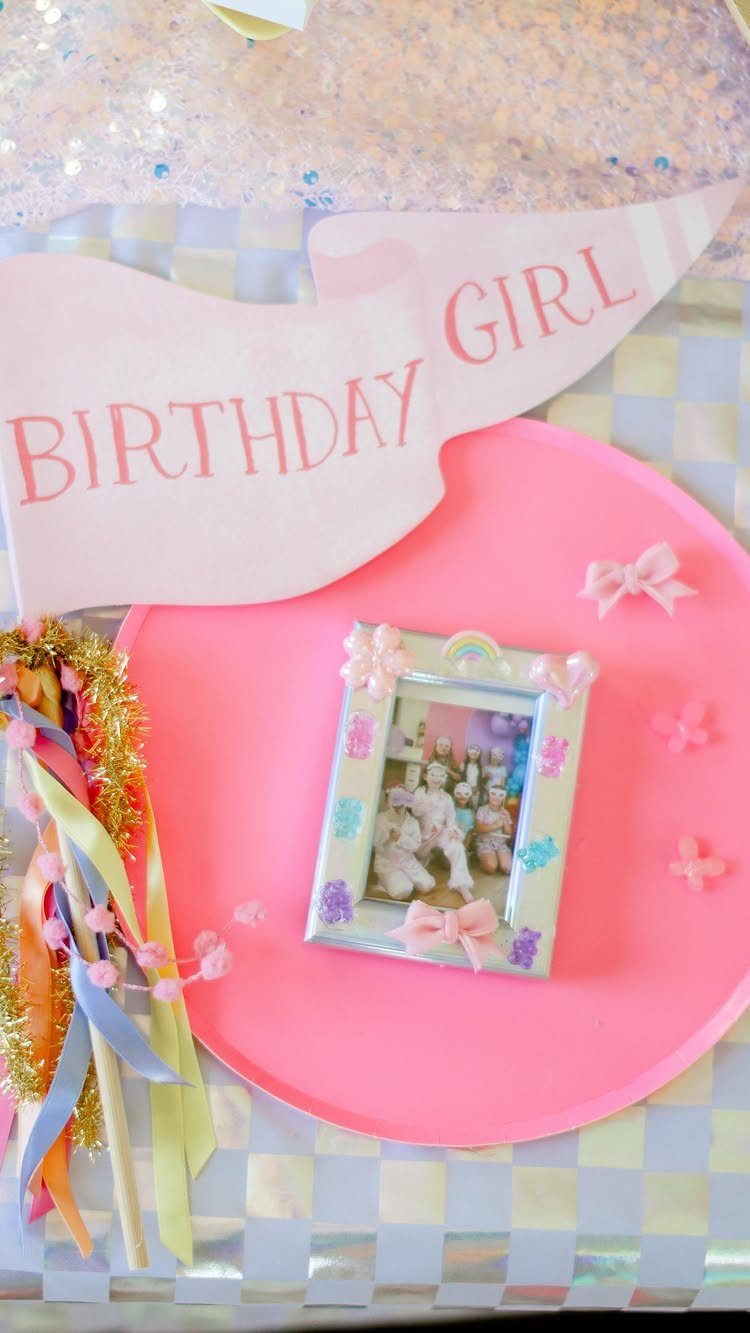 Decorated photo frame and birthday banner on a pink heart-shaped surface.