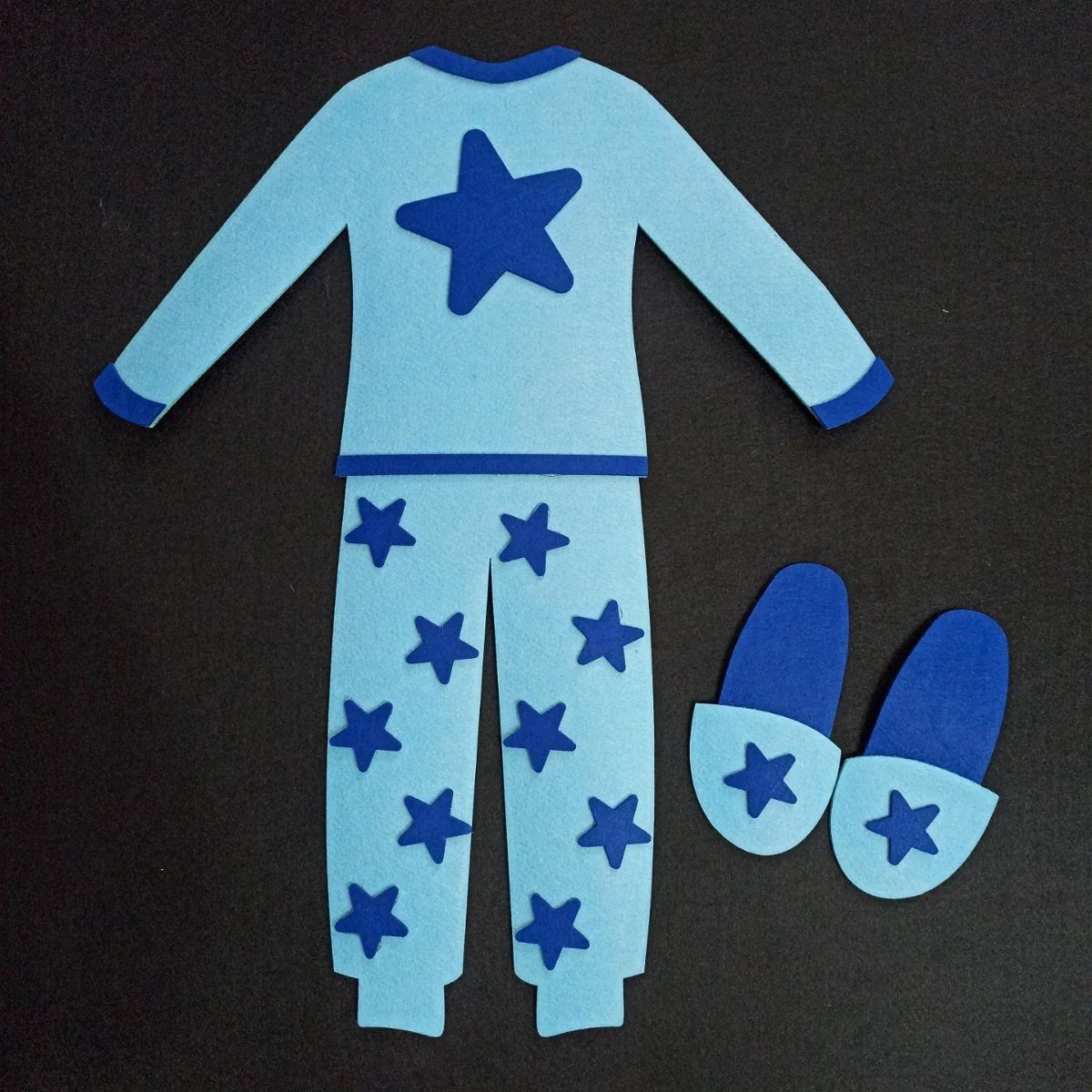 Blue felt pajama set and slippers with star patterns on a black background