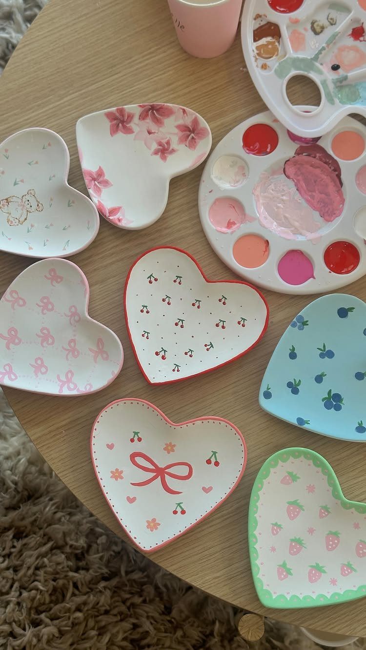 Heart-shaped ceramic trays with hand-painted fruit and flower designs on a wooden table