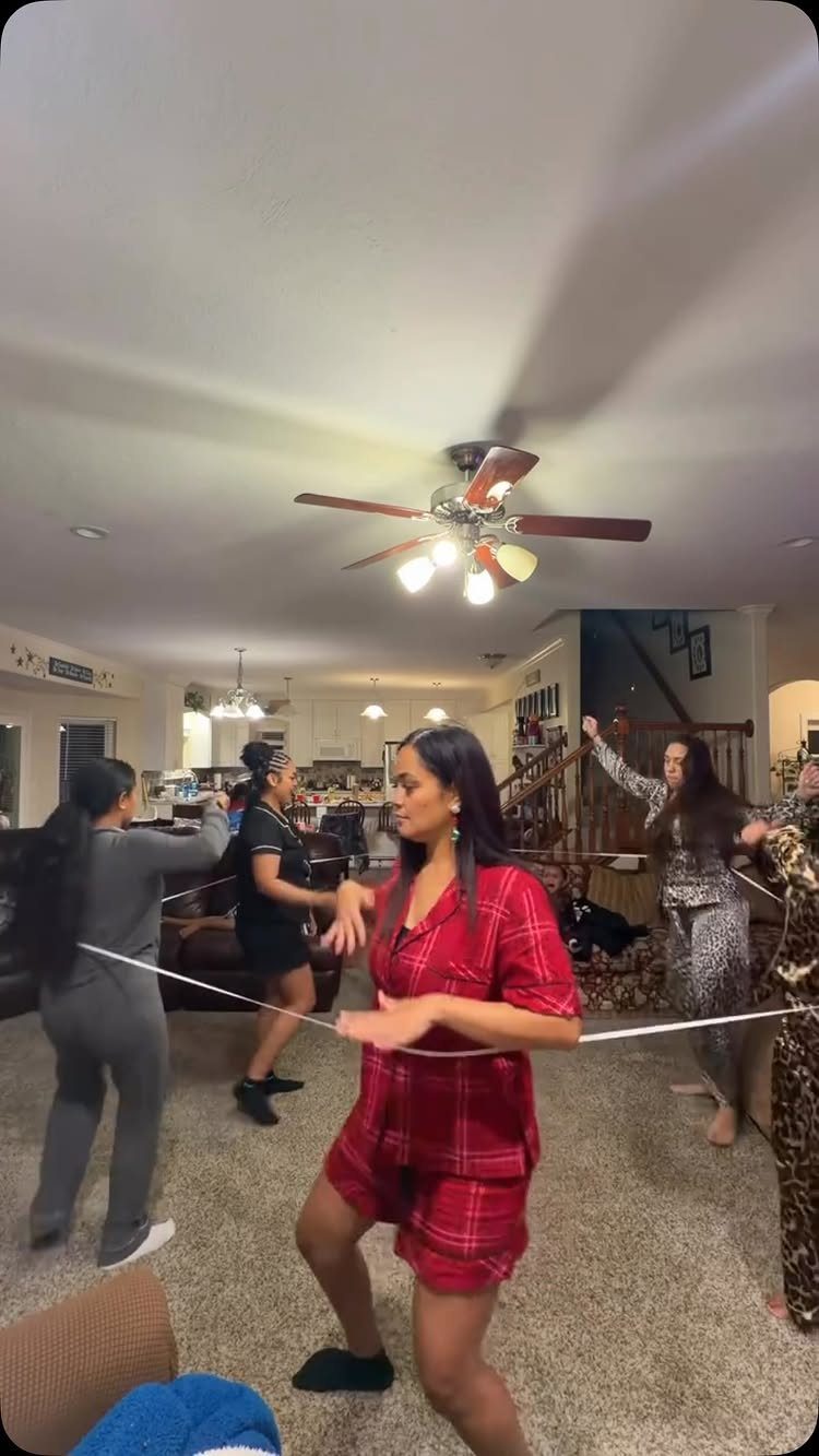 Women in pajamas playing a game with a white string in a living room