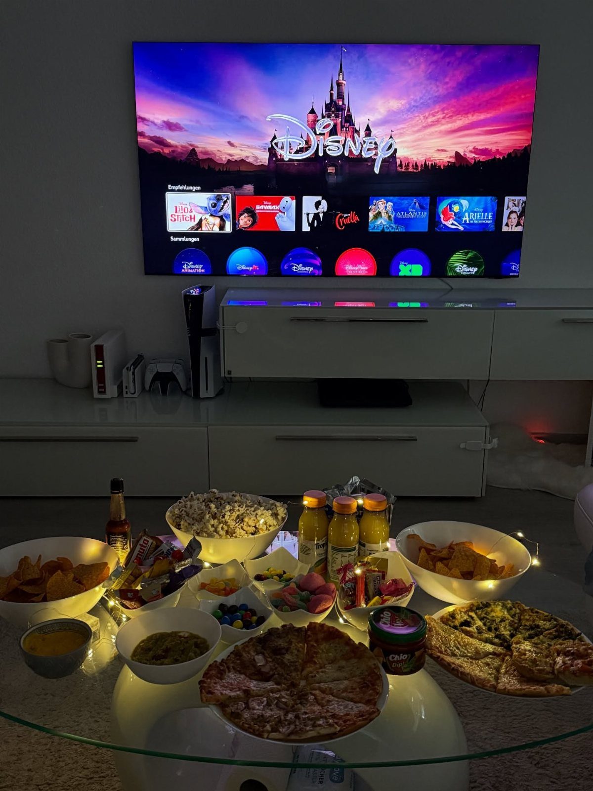 Disney+ menu on a television with pizza, popcorn, and snacks on a table