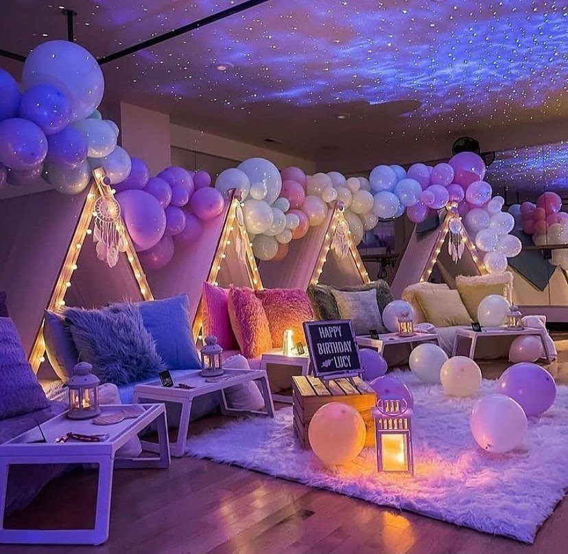 Teepee tents and balloons in a room with a starry night ceiling projection.