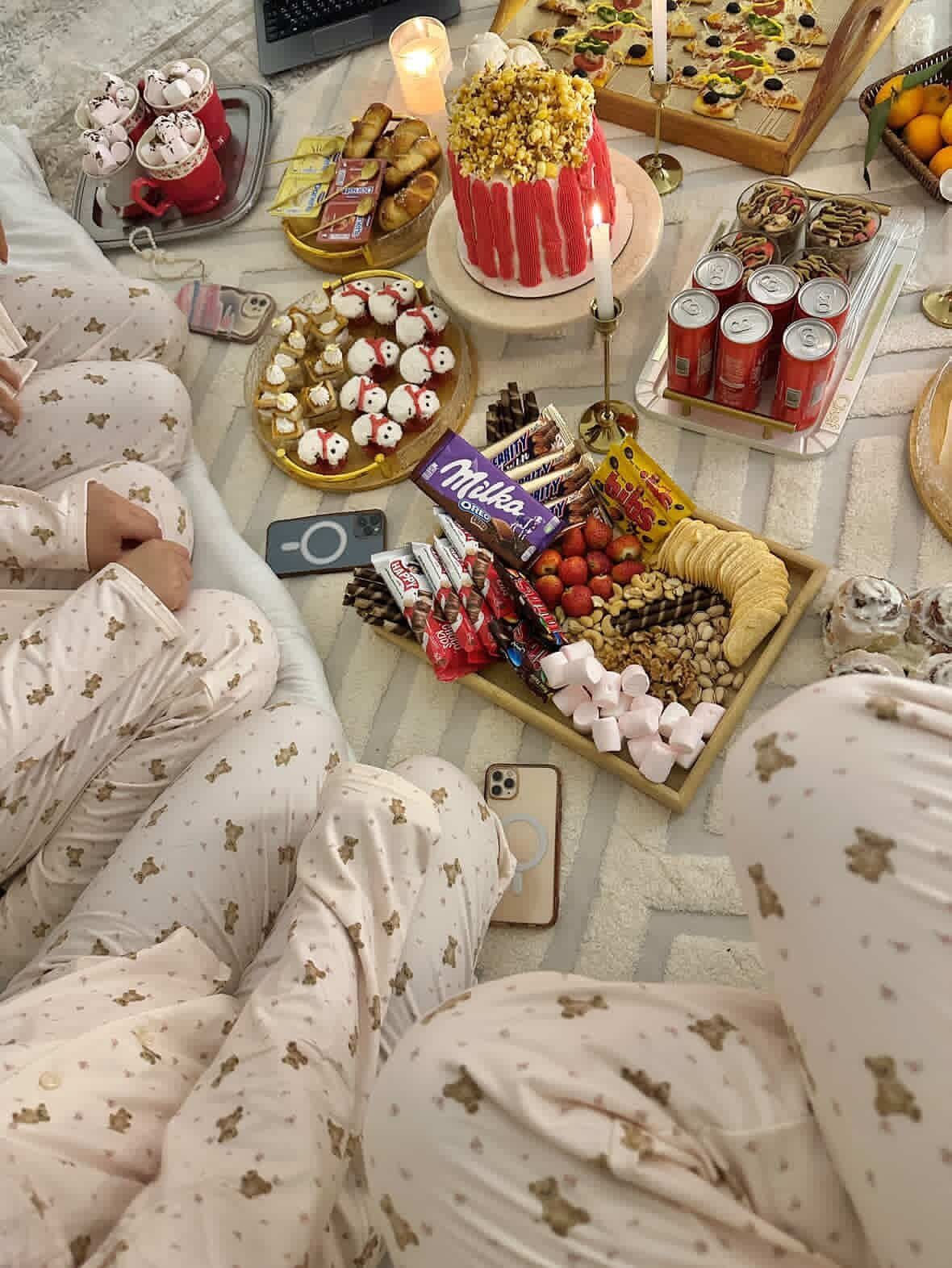Assorted snacks and a popcorn cake spread on a rug for a pajama party.