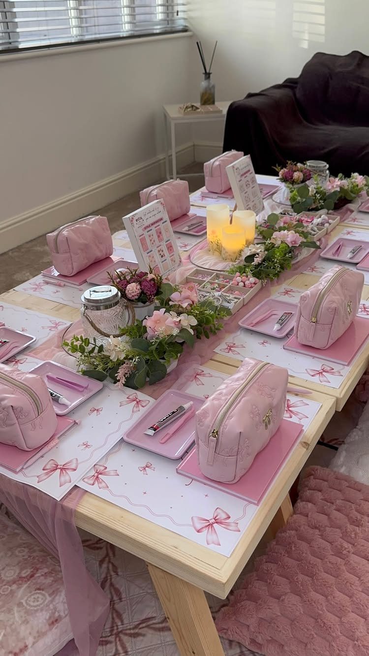 Pink party table setting with cosmetic bags, floral arrangements, and candles for spa night.