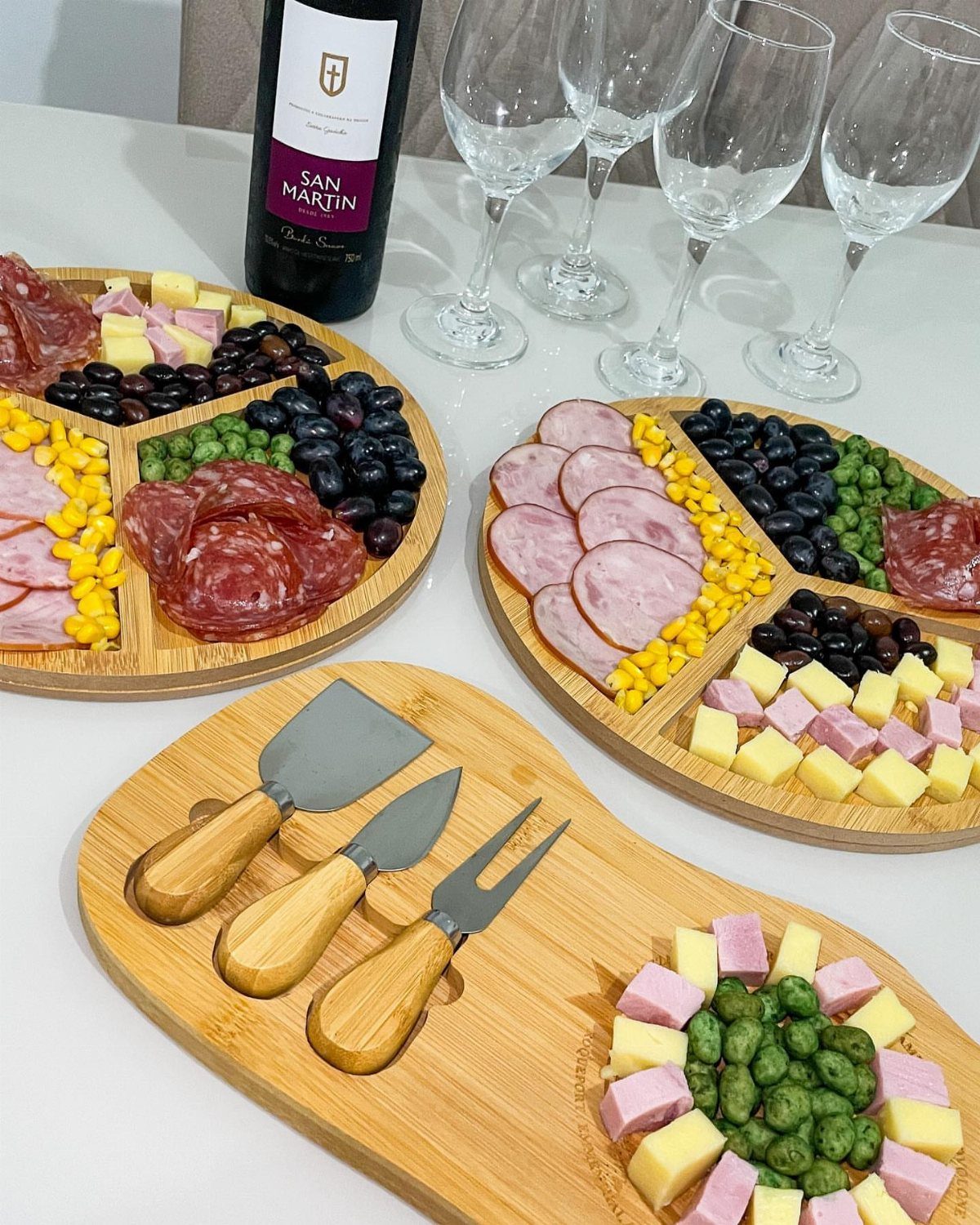 Charcuterie boards with meats and cheeses next to a wine bottle and glasses.