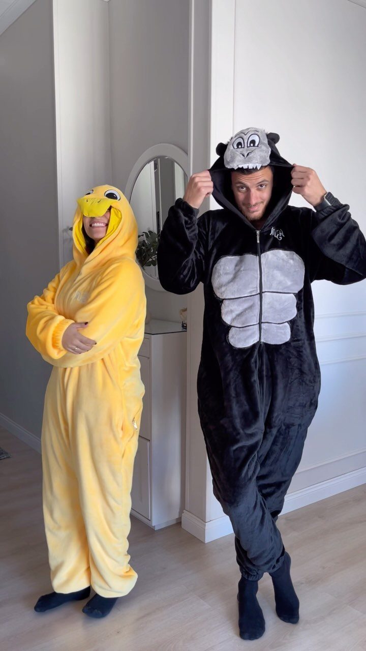 Man and woman wearing black gorilla and yellow chick animal onesie pajamas.