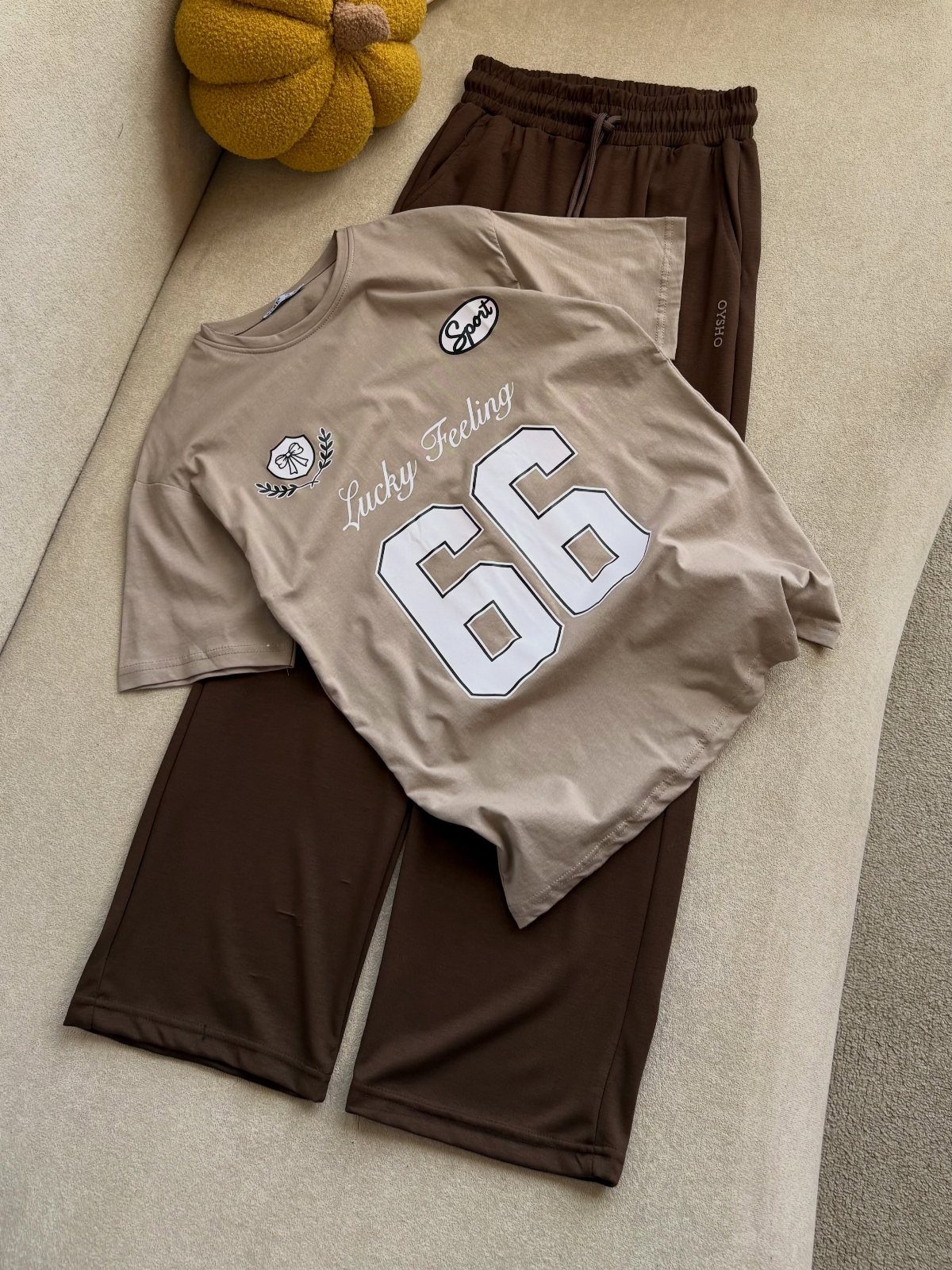 Tan oversized t-shirt and brown sweatpants laid flat on a beige surface.