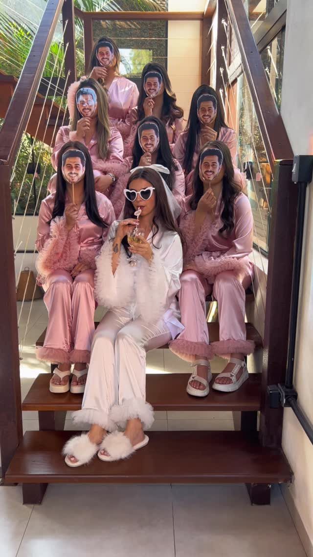 Women in pink and white satin pajamas holding face masks of a man.