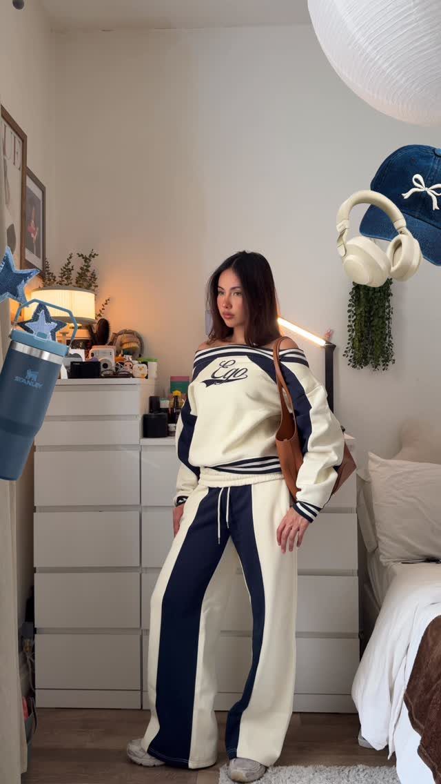 Woman wearing a cream and navy blue lounge set in a bedroom