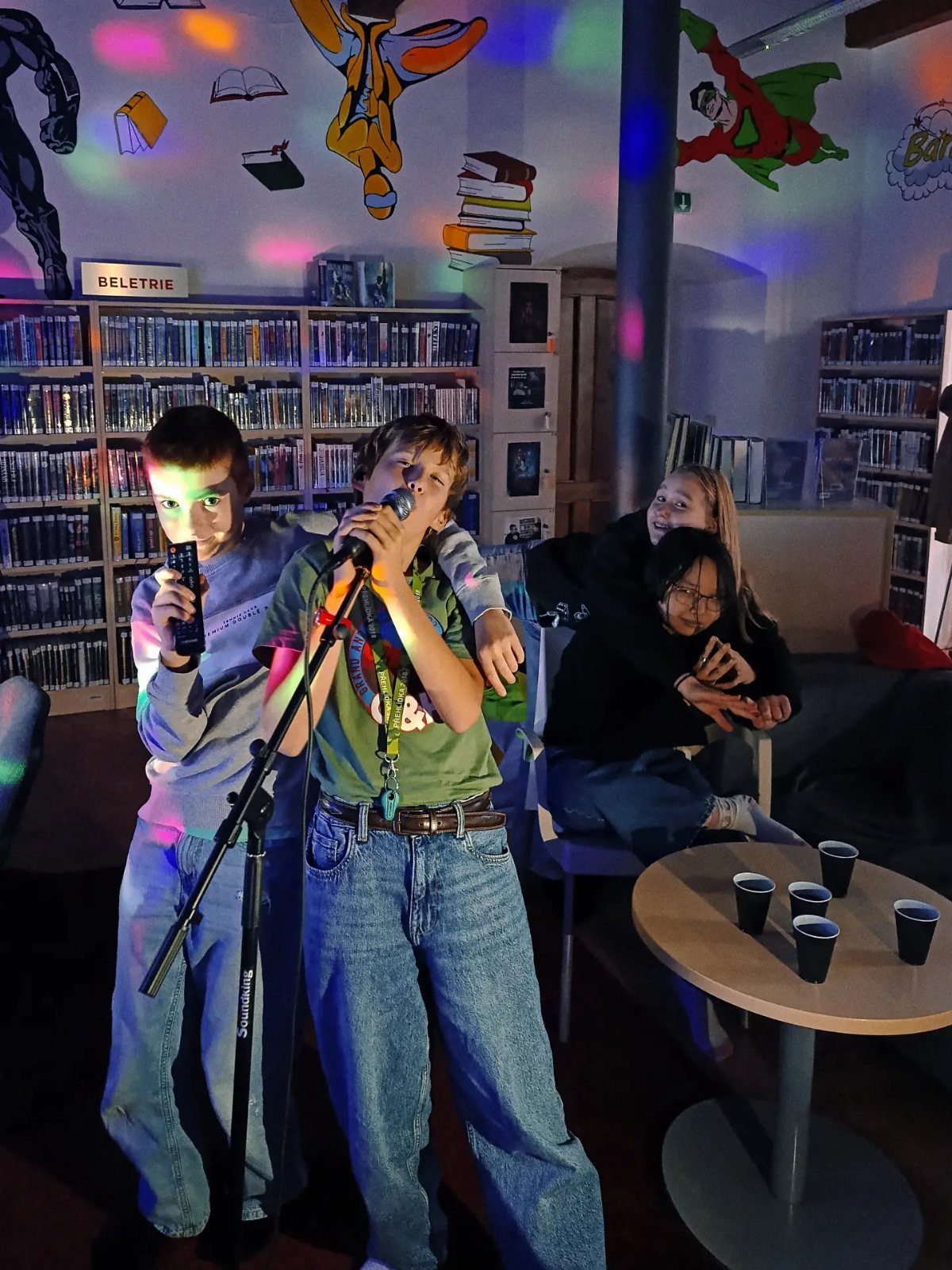Teenager singing into a microphone with friends in a room with disco lights.