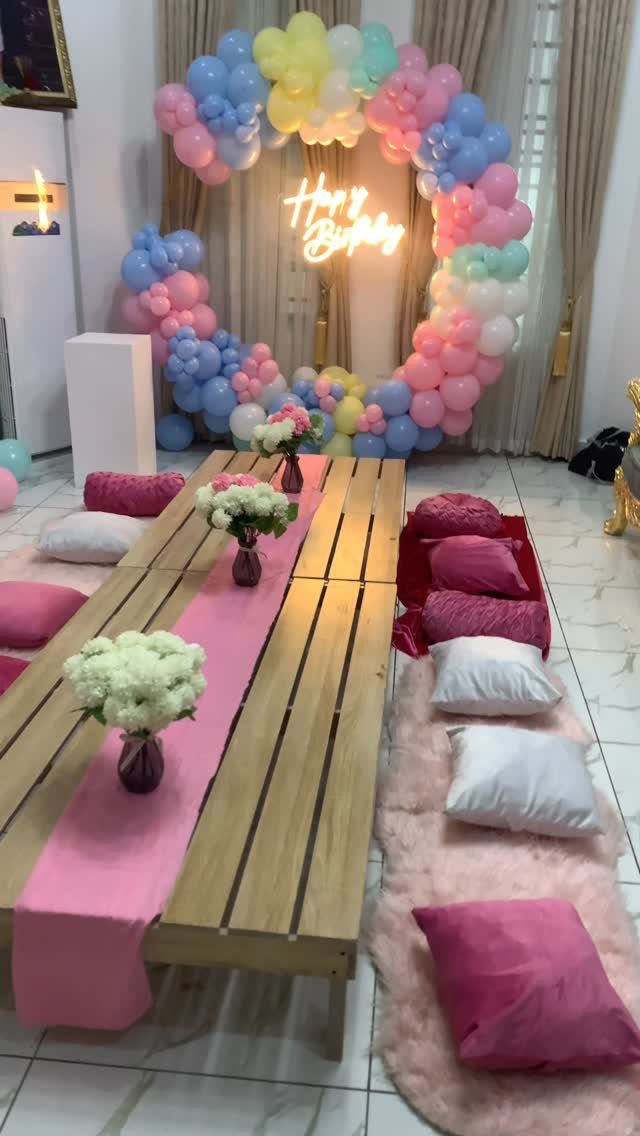 Low wooden table with pink runner and decorative pink and white floor pillows.