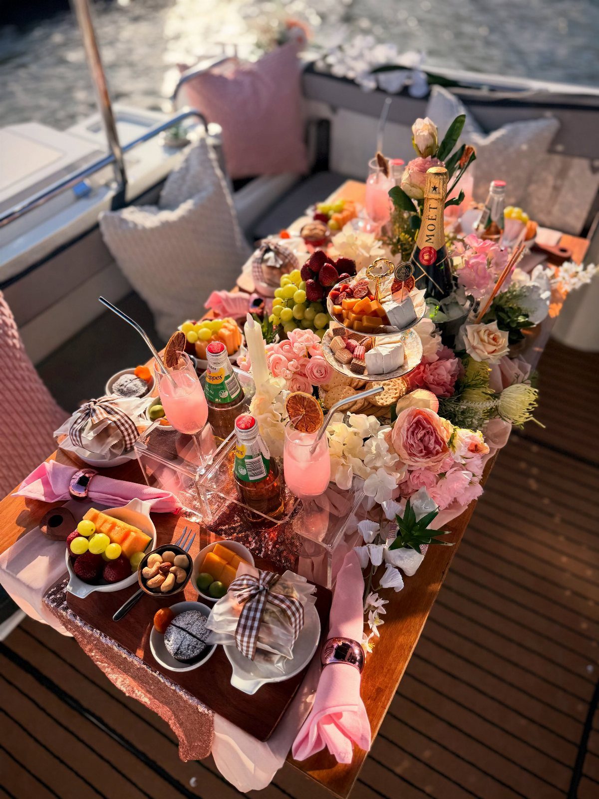Lavish food and flower spread on a wooden table aboard a boat.