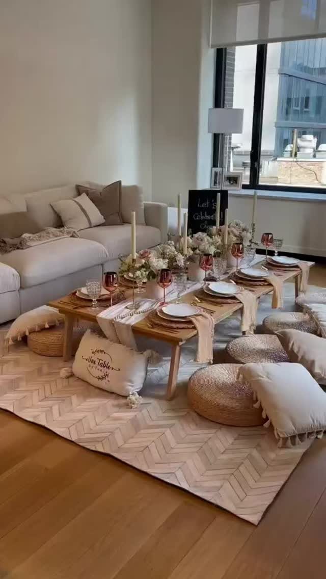 Low wooden dining table with floral centerpieces and cushions in a modern living room.
