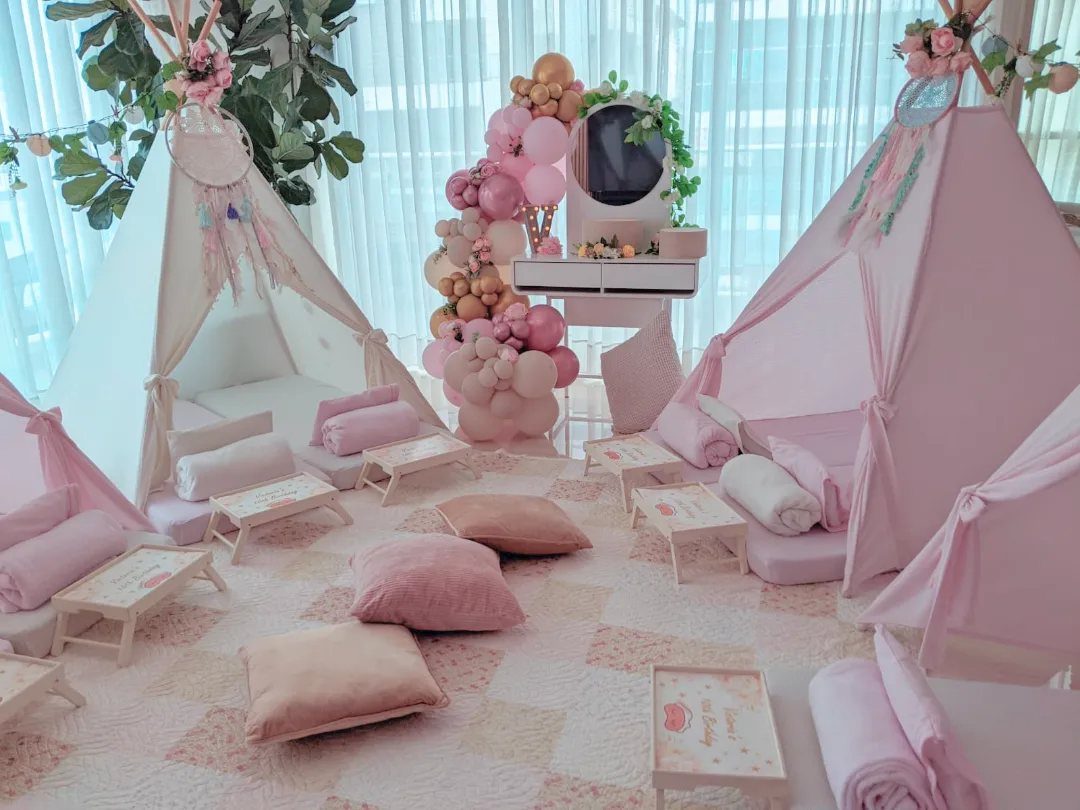 Pink and white indoor teepee tents with cozy pillows and blankets on a rug.
