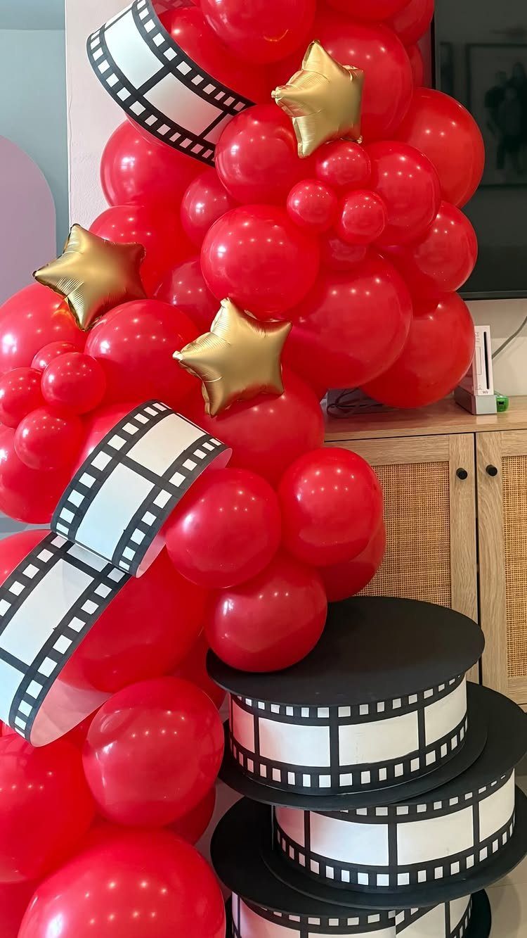 Red and gold star balloons with film strip ribbons for a movie party.