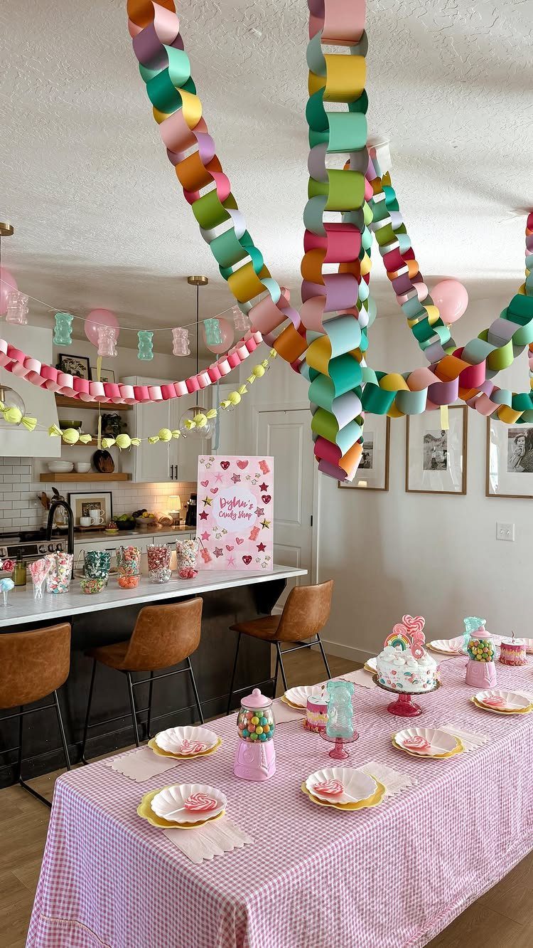 Colorful paper chain garlands and a pink checkered table set for a party.