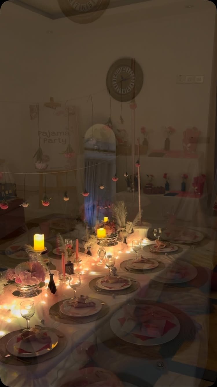 Decorated party table with glowing candles, plates, and warm ambient string lighting.