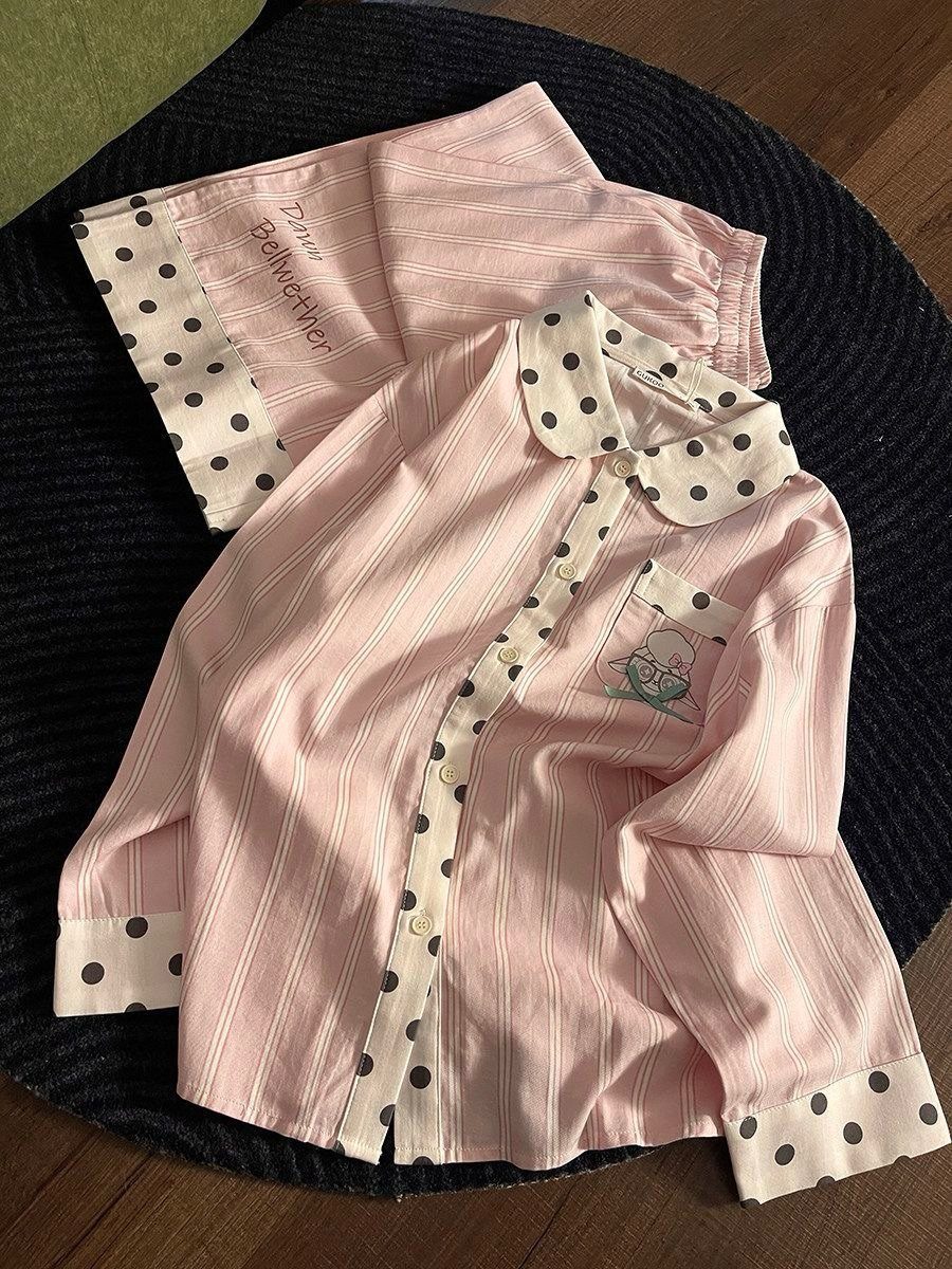 Pink and white striped pajama set with polka-dot trim on a dark rug