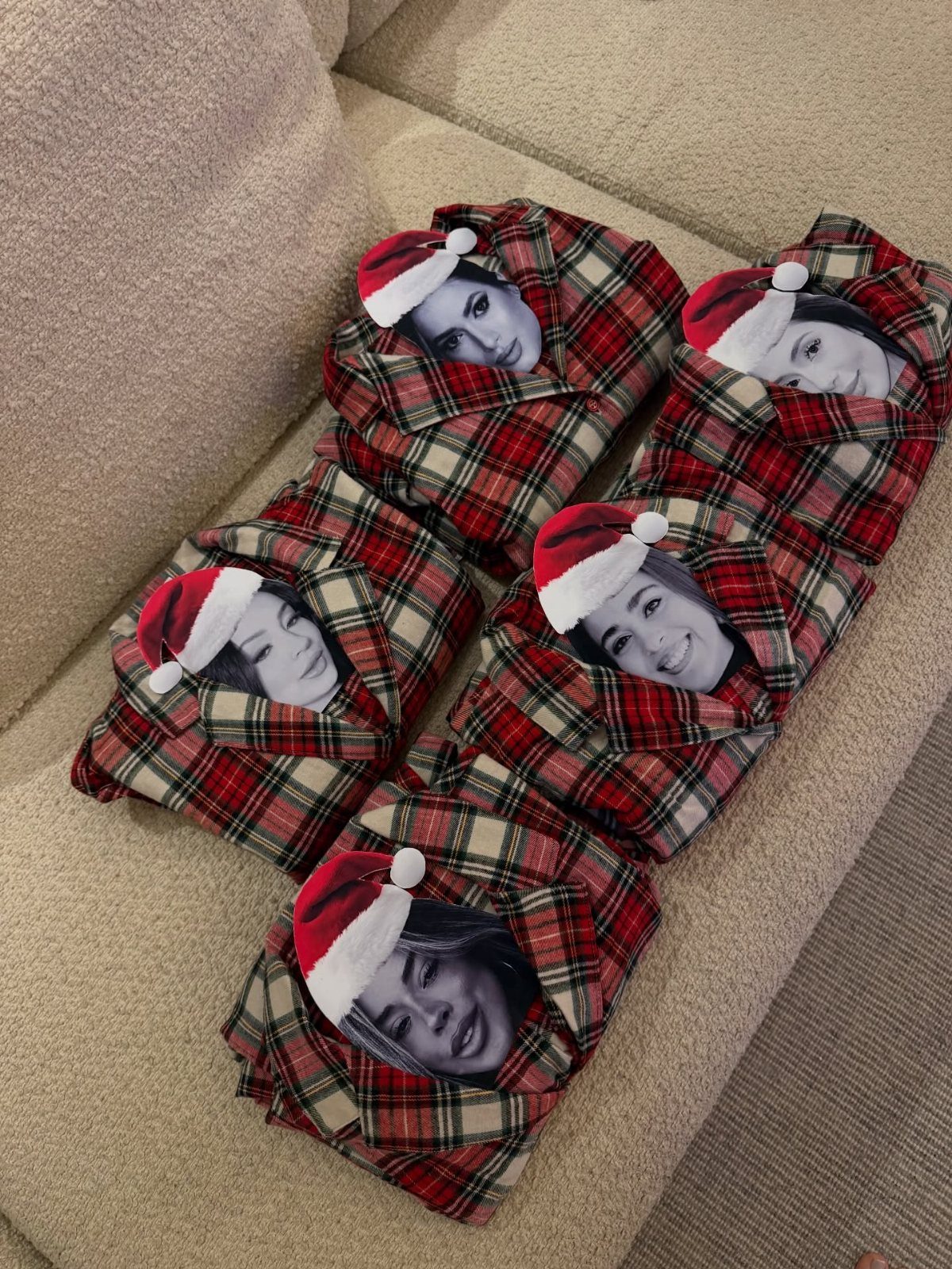 Plaid pajamas with printed faces wearing Santa hats resting on a beige sofa