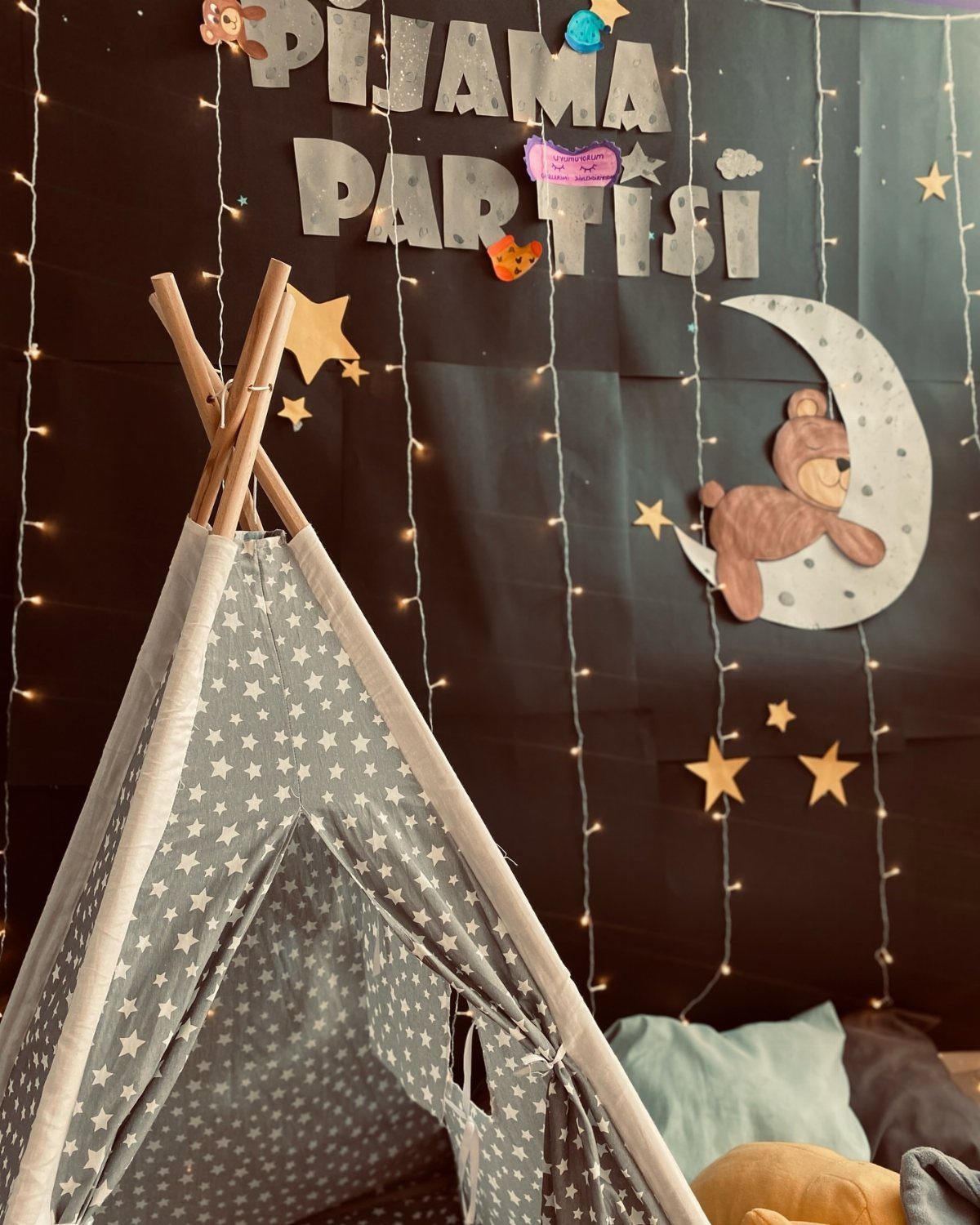 Star-patterned teepee tent with fairy lights and moon decorations for a pajama party.