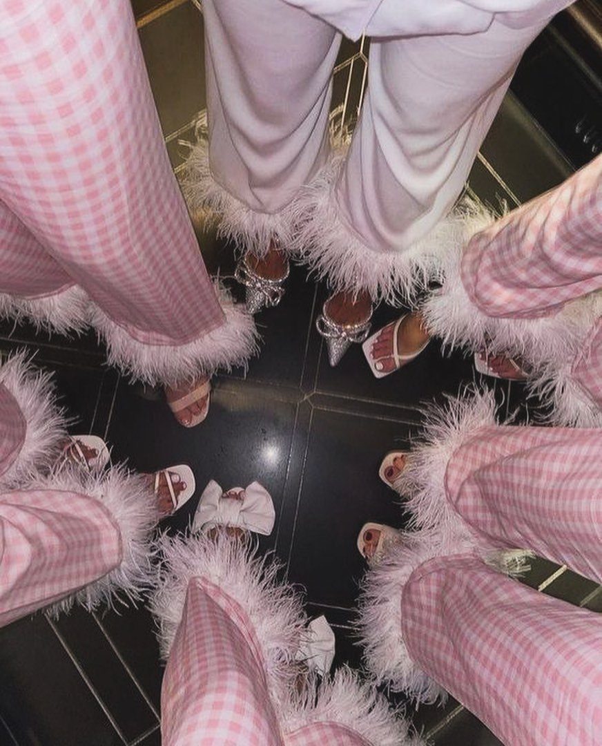 People wearing pink gingham and white fluffy pajama pants standing in a circle.