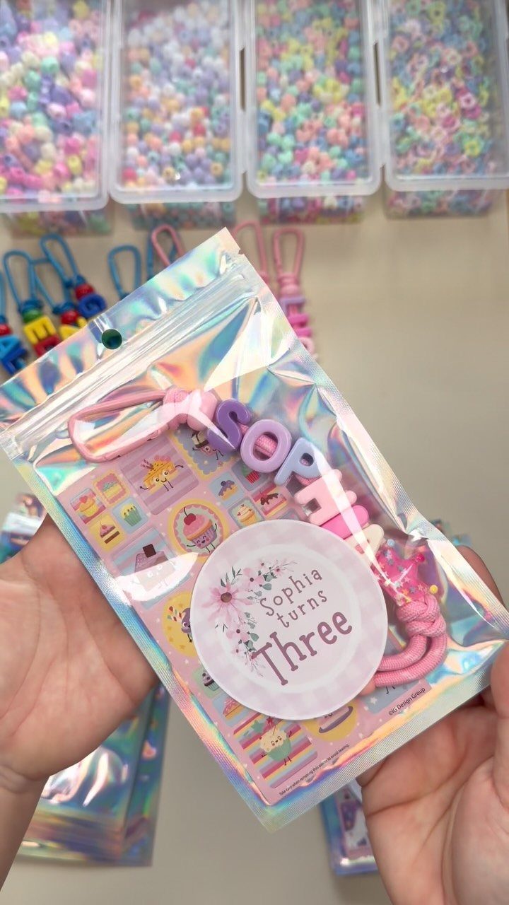 Holographic party favor bag containing a personalized pink beaded bracelet for a child.
