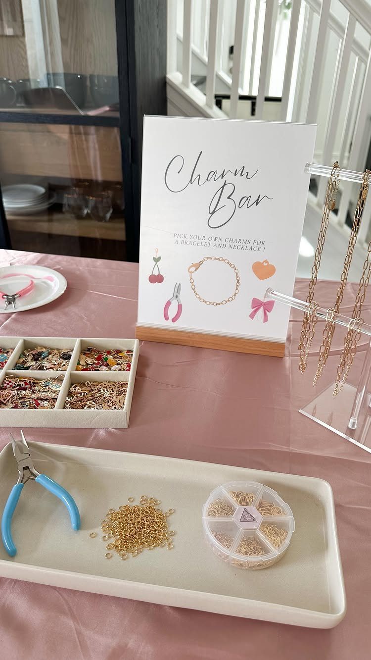 Charm bracelet bar setup with gold chains, colorful charms, and jewelry tools.