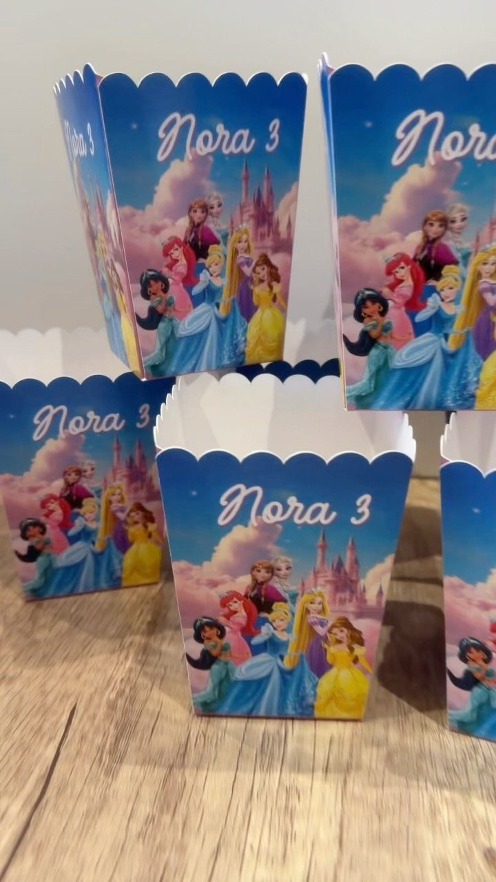Princess themed popcorn boxes with Nora 3 text on a wooden table