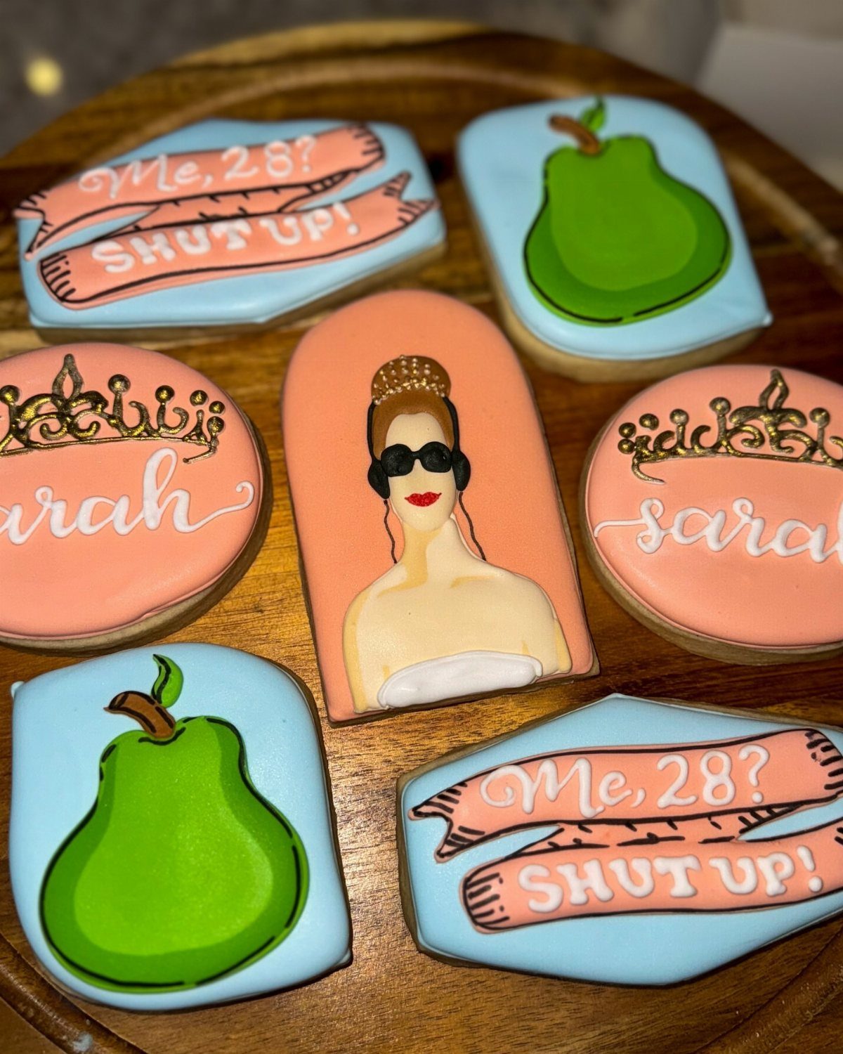 Decorated sugar cookies with princess themes, pears, and birthday text on a platter.