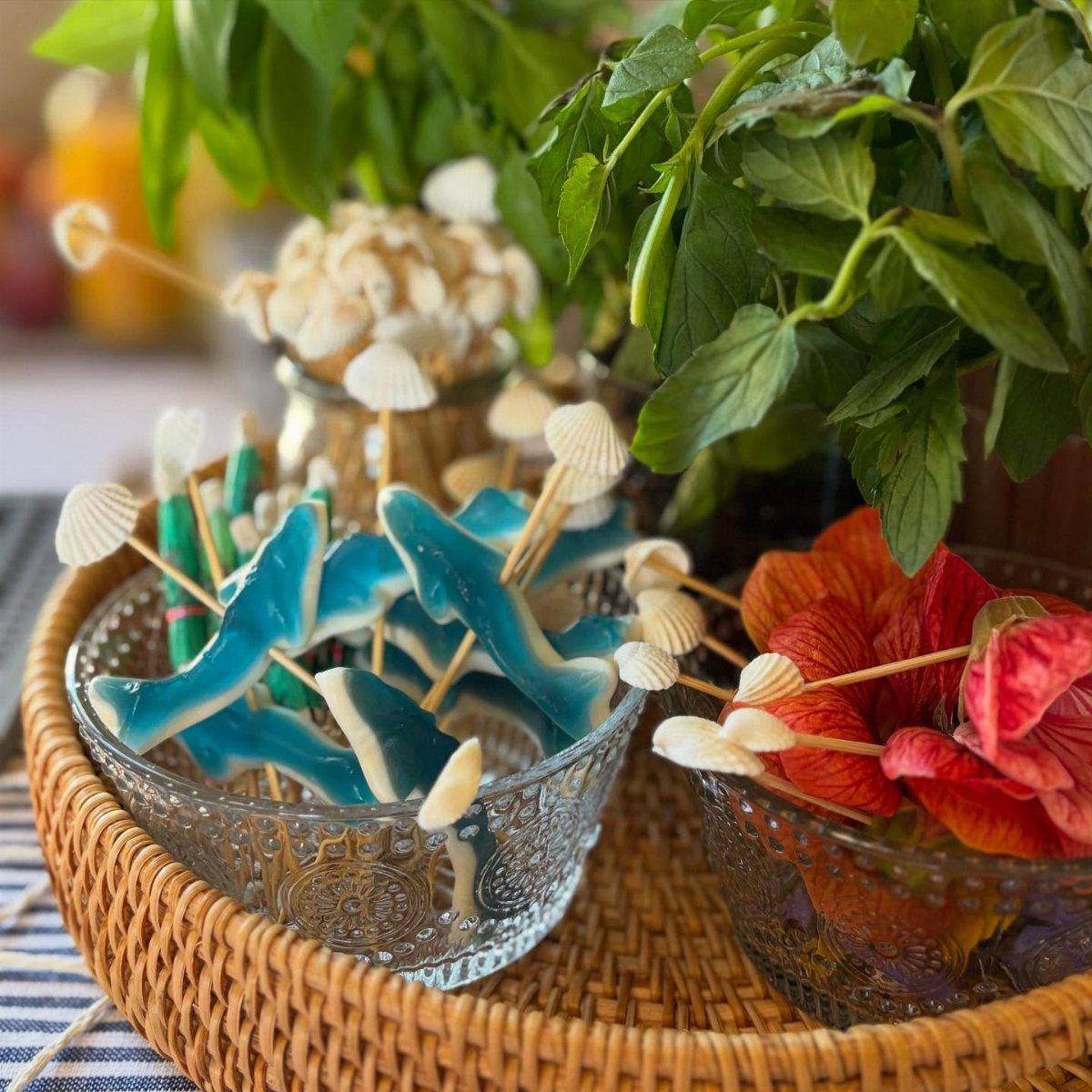 Blue and red gummy candies on skewers in glass bowls on a tray.