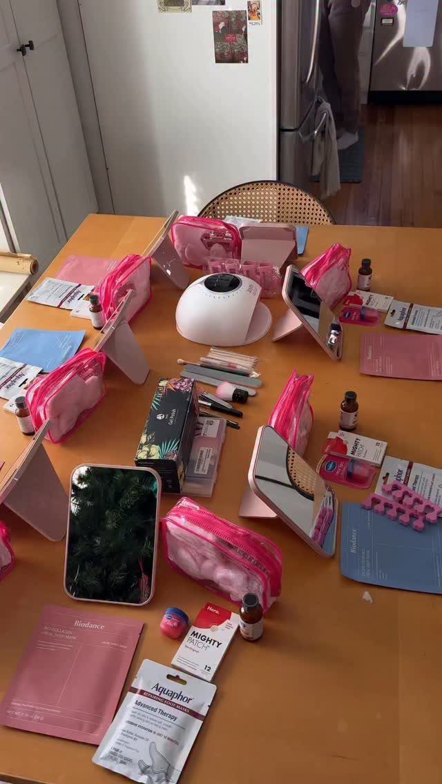 Skincare products and pink pouches arranged on a wooden table for a spa party.