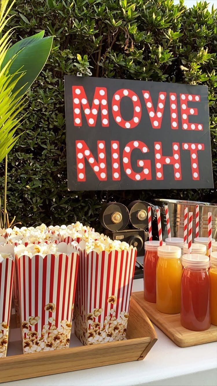 Popcorn bar with striped boxes and colorful drinks under a Movie Night sign.