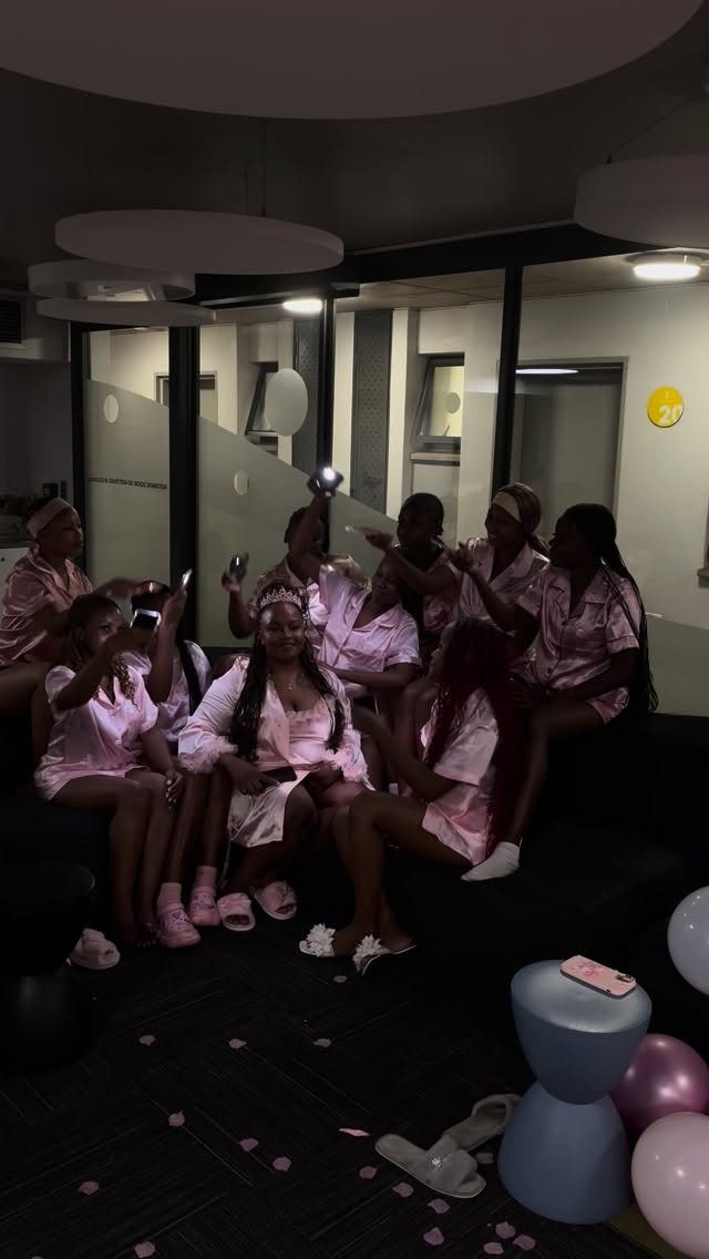 Women in pink satin pajamas sitting on a sofa during a pajama party.