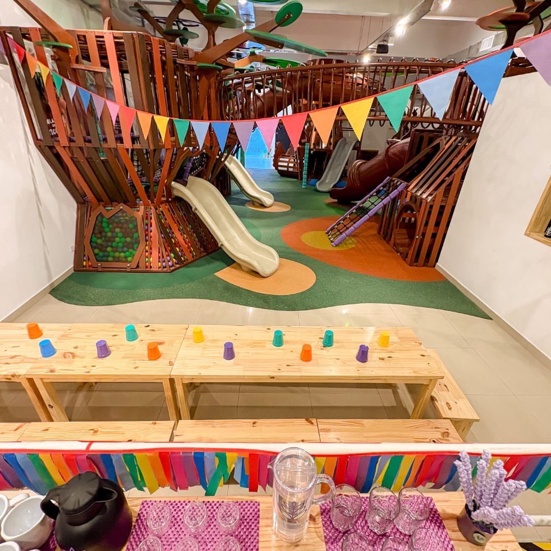 Indoor playground with wooden slides, ball pit, and party tables with colorful bunting.