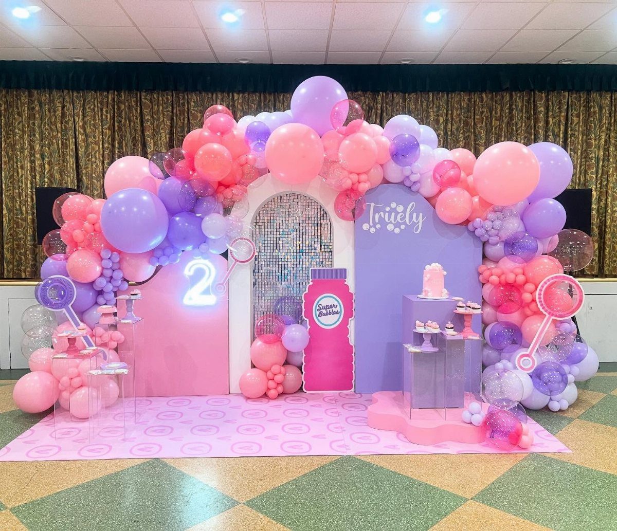 Pink and purple balloon arch and backdrop for a second birthday party setup.
