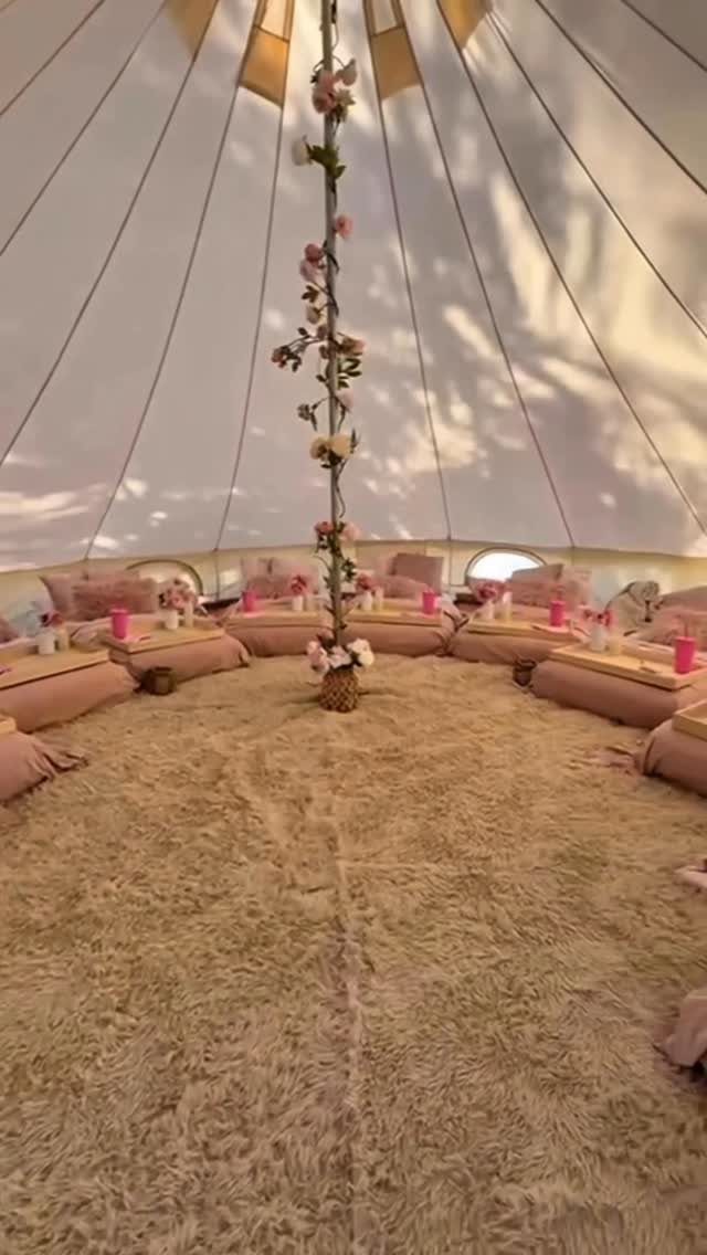 Cozy bell tent interior with pink floor mattresses and floral decorations for guests.