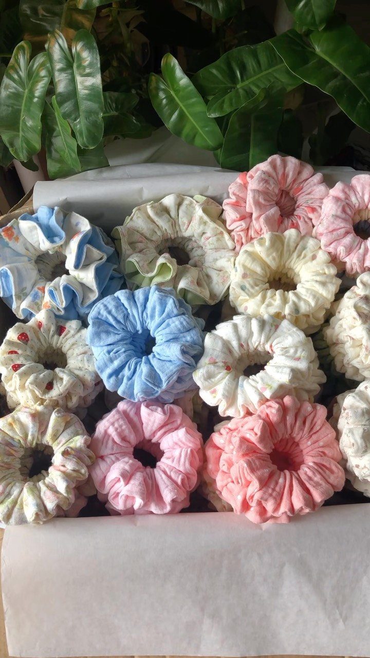 Pastel colored fabric scrunchies packed together in a white cardboard box.