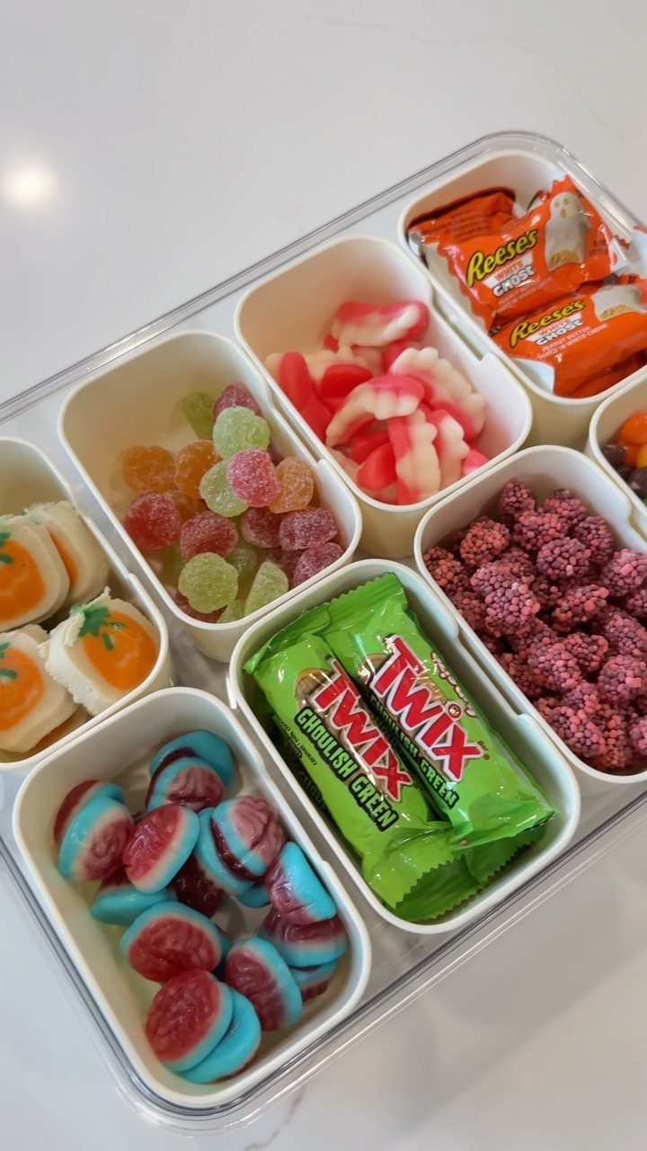 Assorted colorful candies and chocolates arranged in a white divided plastic container.